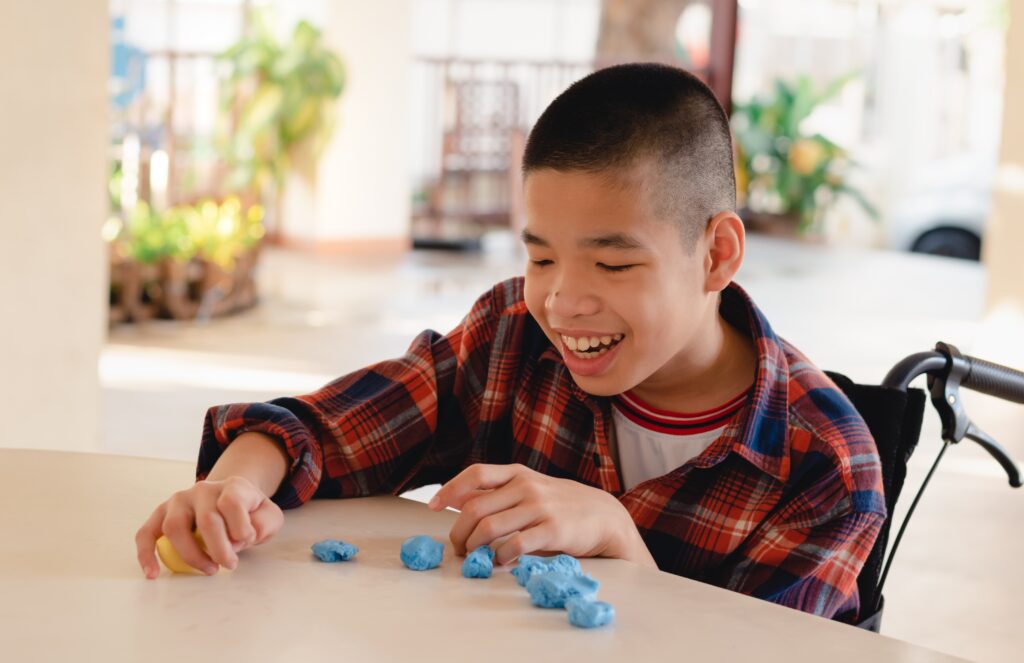 Asian disabled child on wheelchair molding clay